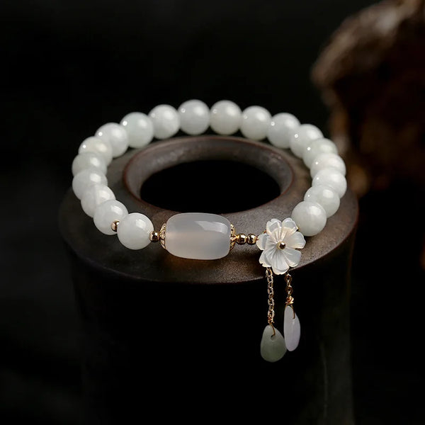 White beaded bracelet with floral charm on a dark background